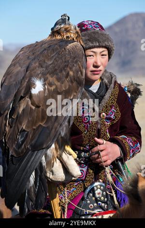 Mongolian Eagle Hunter on horseback with Golden Eagle (Aquila chrysaetos) at the Eagle Festival in Mongolia; Olgii, Mongolia Stock Photo