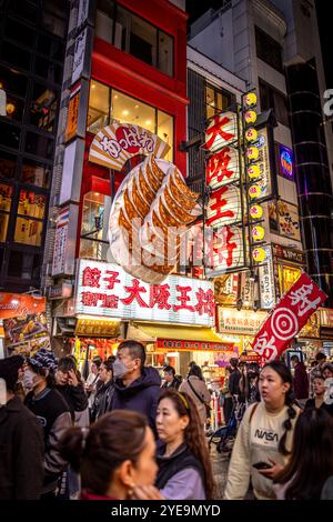 Tourists in dotonbori, osaka night under gyoza restaurant sign Stock Photo