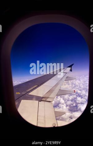 View of wing and clouds through airplane window Stock Photo