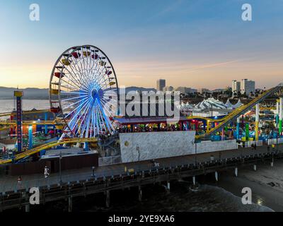 The Santa Monica Beach Pier in California, with Pacific Park at Sunset from a UAV Drone View showing the City Lights Stock Photo