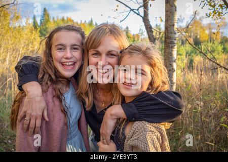 Close-up portrait of a mother embracing her two daughters and smiling at the camera in a rural setting in Beckwith Township at Carleton Place in th... Stock Photo