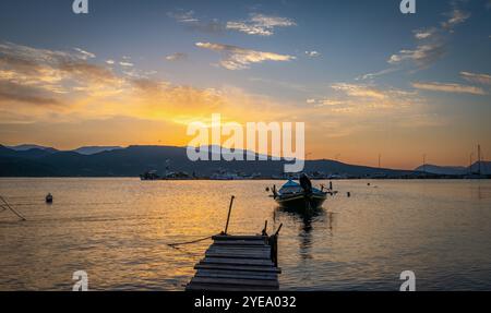 Small boats moored in a harbour on a morning with a beautiful golden sunrise and sky clouds. Stock Photo