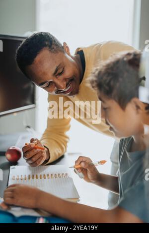 Smiling man helping son doing homework at home Stock Photo