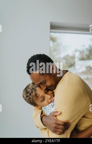 Affectionate father embracing son at home Stock Photo