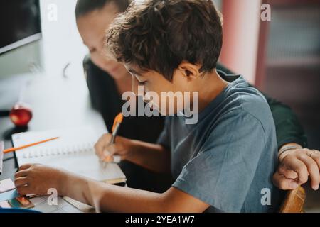 Mother helping son doing homework while sitting at home Stock Photo
