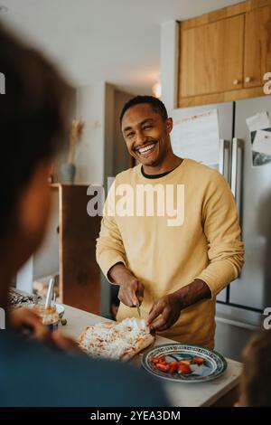 Happy mature man making pizza while standing in kitchen at home Stock Photo