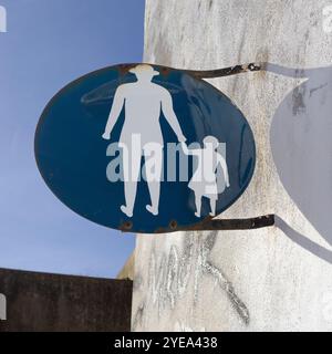 Charming pictogram sign of an adult holding the hand of a child, mounted on the side of a white building; Lagos, Faro, Portugal Stock Photo