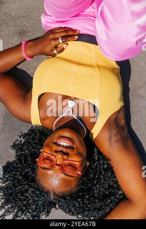 Directly above shot of smiling woman with curly hair lying down at sunny day Stock Photo