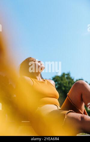 Young woman with eyes closed posing under blue sky Stock Photo