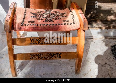A beautiful vintage wooden stool with carvings, and a embroidered seat. Stock Photo