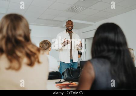 Happy male teacher gesturing while teaching high school students in classroom Stock Photo
