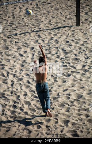 Informal Beach Volleyball Players enjoying the day looking at people with the ball in play on the sand Stock Photo