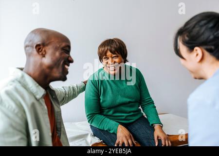 Happy son and mother with female doctor sitting in medical examination room Stock Photo