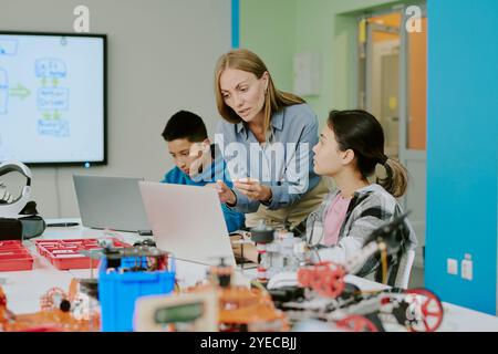 Caucasian computer science teacher looking at laptops screen while explaining codes to schoolgirl during lesson at school Stock Photo