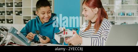 Website banner of two classmates building robot on wheels together in light spacious classroom Stock Photo