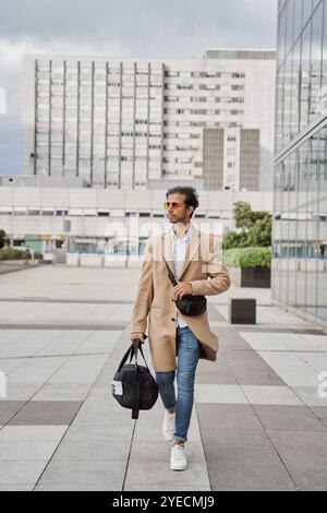 An Indian man is on his way to the gym. He is carrying his gym bag in his other hand. He is wearing a casual suit with a pocket square. Stock Photo