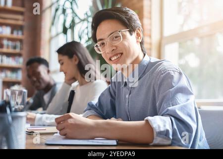 Smiling asian guy taking notes while business meeting with colleagues Stock Photo