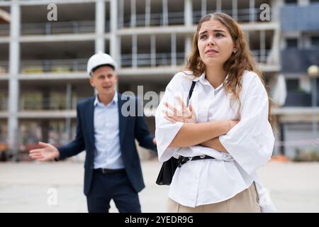 Upset young woman and egineer in construction plant Stock Photo