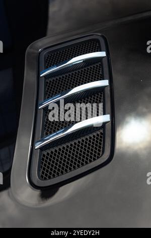 Close-up of chrome-plated air intakes on the hood of a black car, showcasing a blend of style and performance that enhances the vehicle's aggressive a Stock Photo