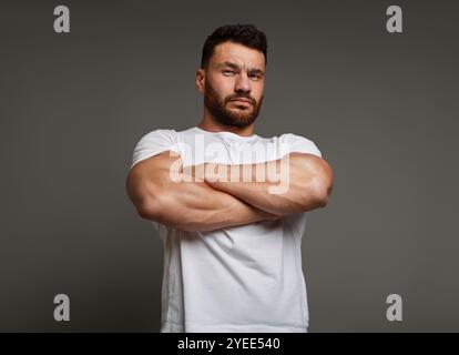 Suspicious young man with crossed big muscular arms Stock Photo