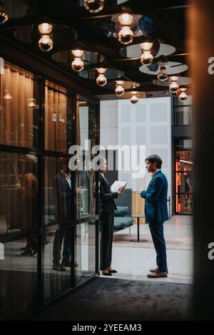 Side view of male and female entrepreneurs sharing strategies while standing at lobby Stock Photo