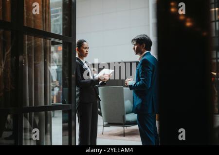 Female professional discussing with young male colleague while standing by wall Stock Photo