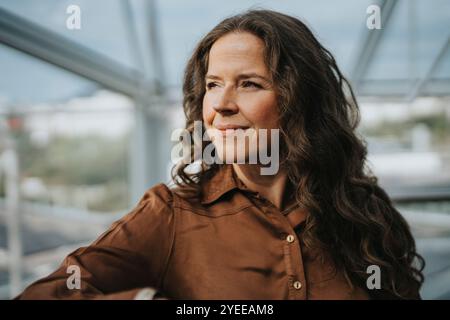 Smiling mature businesswoman with long brown hair looking away Stock Photo