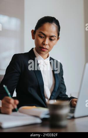 Businesswoman writing in diary while working in office Stock Photo