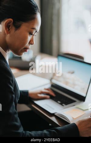 Side view of businesswoman with laptop working at desk Stock Photo