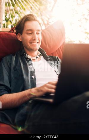 Smiling young man using laptop while sitting in hammock Stock Photo