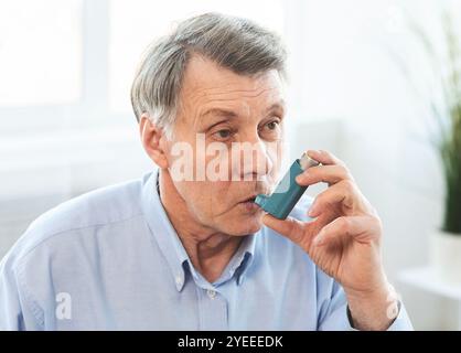 Elderly man using asthma inhaler for allergies Stock Photo
