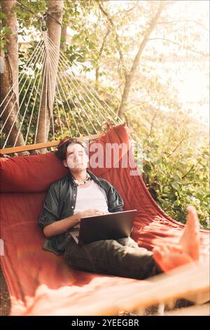High angle view of young man relaxing with laptop in hammock Stock Photo