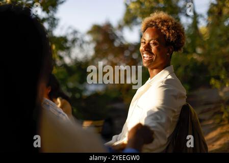Side view of happy young man with curly hair enjoying while sitting with friends in dinner party Stock Photo