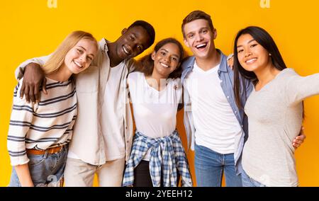 Friendly international group of teenagers taking selfie over yellow background Stock Photo