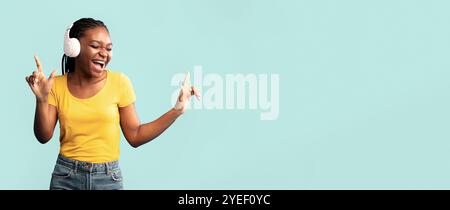 Cheerful African Lady In Earphones Singing Posing Over Blue Background Stock Photo