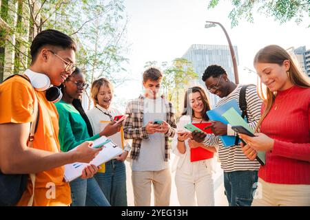 Diverse College Students Gather Outdoors on University Campus, Smiling While Using Mobile Phones and Holding Books. Teenagers Representing Modern Digital Learning and Social Connection with Cellphone. High quality photo Stock Photo