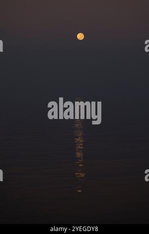 Super moon setting over a calm ocean Stock Photo
