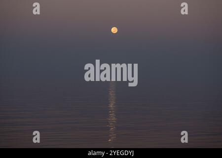 Super moon setting over a calm ocean during sunrise in the Timor Sea Stock Photo