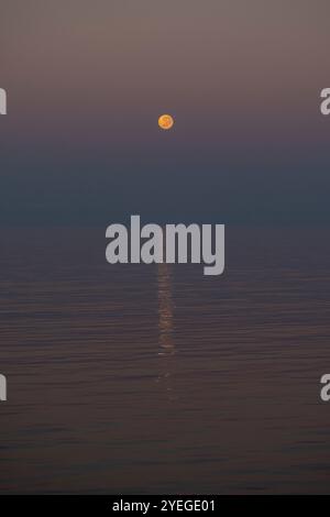 Super moon setting over a calm ocean during sunrise in the Timor Sea Stock Photo