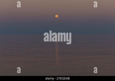 Super moon setting over a calm ocean during sunrise in the Timor Sea Stock Photo