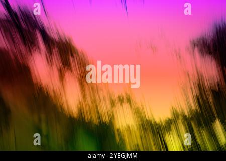 A blurry image of a field with a pink and purple sky. The sky is filled with clouds and the grass is green. The image has a dreamy and peaceful mood Stock Photo