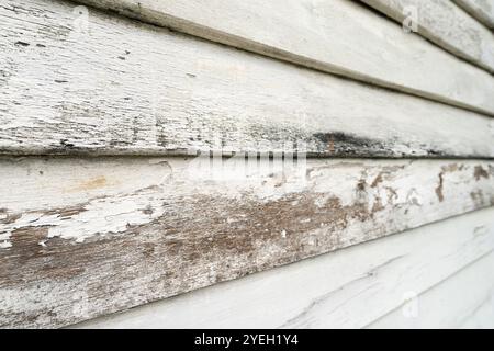 Close-up view of the old wooden building boards chipped and peeling painted white from old paint. Stock Photo