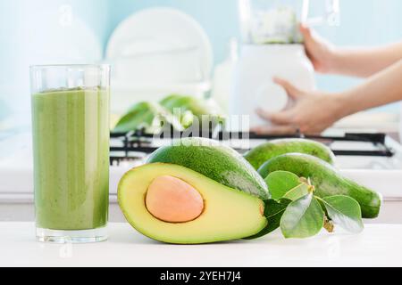 Fresh avocado smoothie and ripe green avocados on kitchen table Stock Photo
