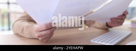 Serious grey haired woman studies reports sitting at table Stock Photo