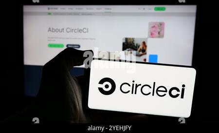 Person holding smartphone with logo of Circle Internet Services Inc. (CircleCI) on screen in front of website. Focus on phone display. Stock Photo