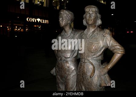 The Women of Steel bronze sculpture in Sheffield, UK, pictured at night in front of the restaurant Cosy Club in October 2024. The Women of Steel sculpture by Martin Jennings was unveiled in 2017 and commemorates the women of Sheffield who worked in the city's steel industry during the First World War and Second World War. Cosy Club opened in July 2024. Stock Photo