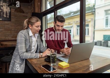 Yong happy business people office workers businessman and businesswoman sitting together in cafeteria, drinking coffee, taking a break from work, talk Stock Photo