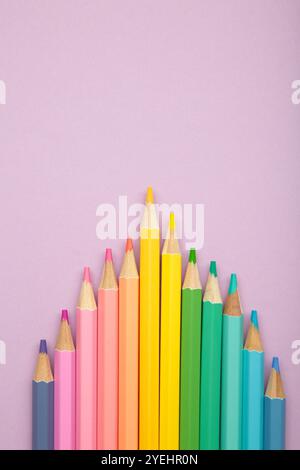 Pastel color pencils on purple background. Vertical photo. Top view Stock Photo