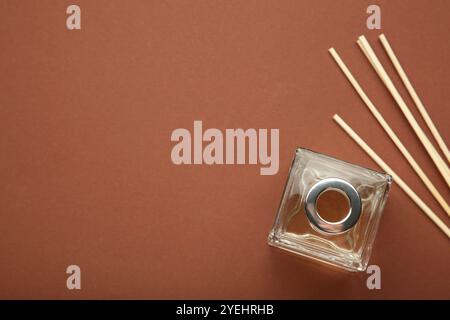 Aroma sticks in glass bottle. Aroma diffuser on brown background. Top view Stock Photo