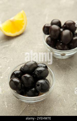 Black olives with lemon on grey concrete background. Top view Stock Photo